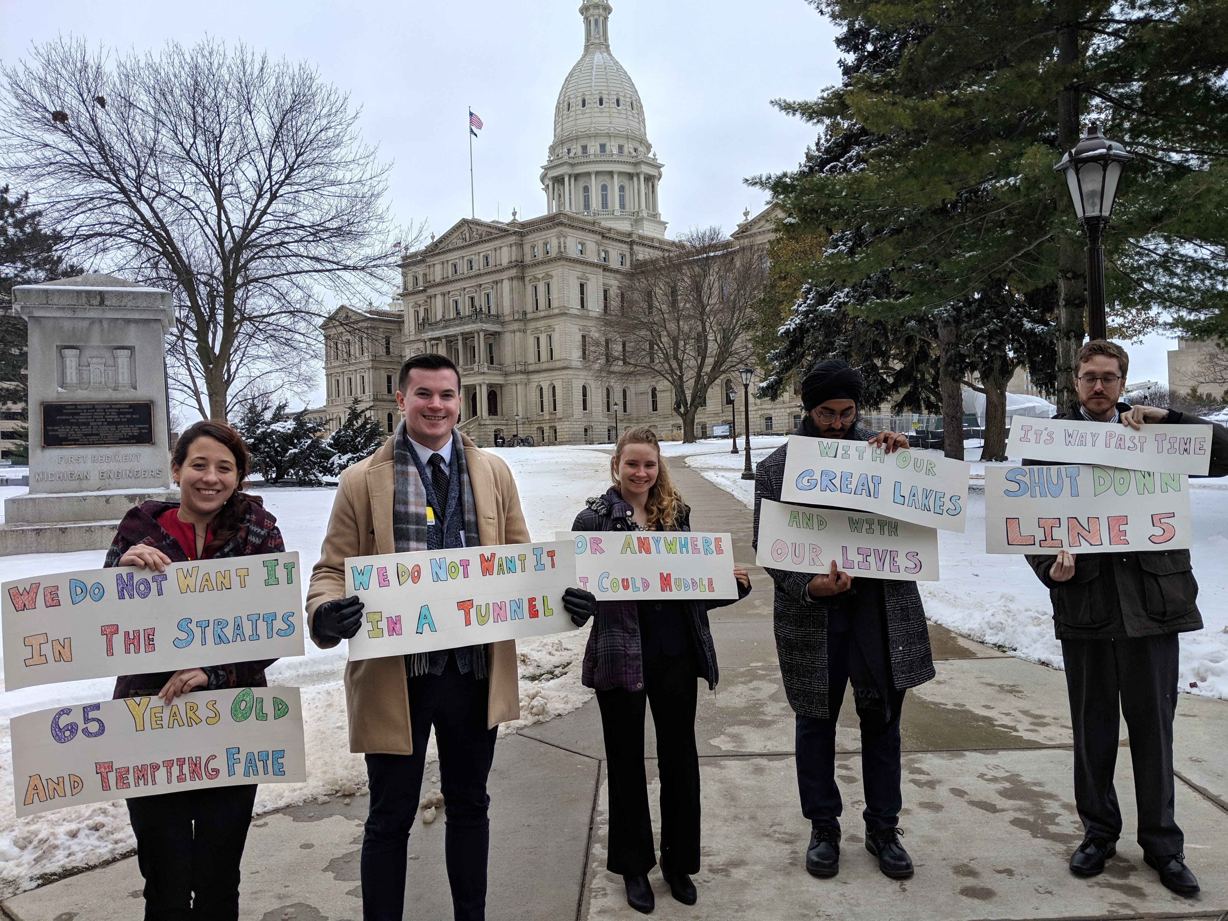Michigan canvass staff holding shut down line 5 / no tunnel signs outside Lansing capitol building in 2018. Credit: Jennifer Schlicht