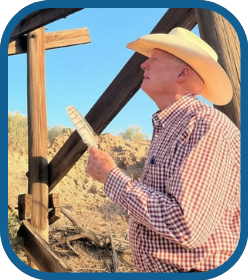Schuyler Wight in a cowboy hat holding a large feather and looking off to the side