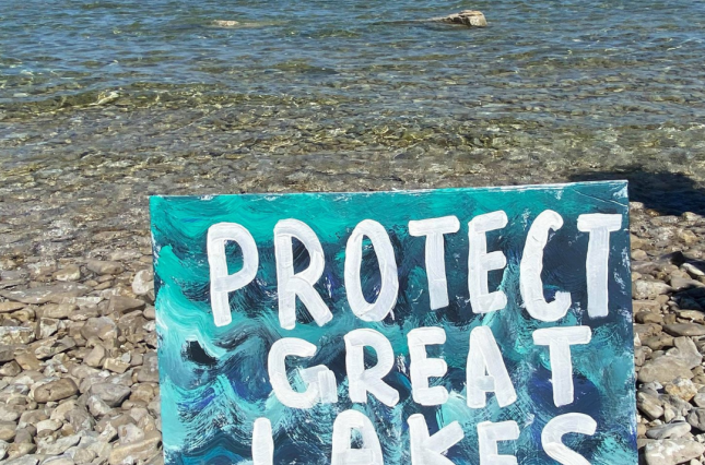 Sign on rocky shoreline of Mackinac Straits: "Protect Great Lakes"