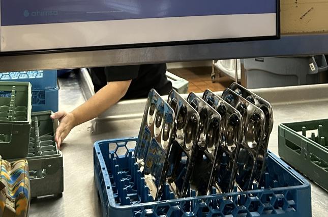A rack of steel lunch trays lined up for washing