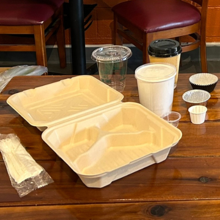 A fiber clamshell container, disposable coffee cups and sauce cups, and plastic disposable utensils