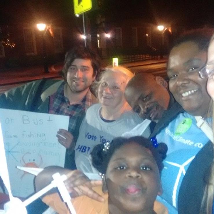 Six people holding wind turbines and signs in favor of offshore wind