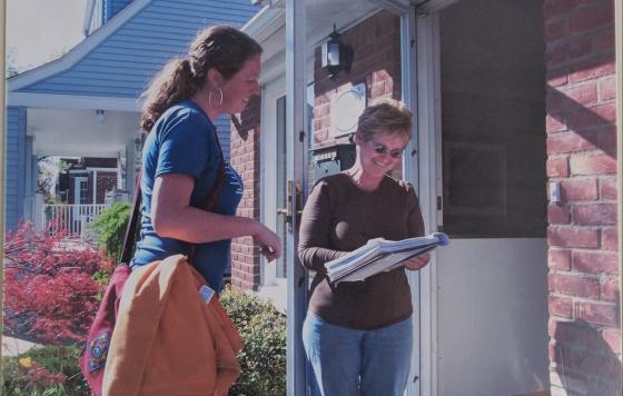 Canvasser at doorstep speaking to a new Clean Water member signing a clipboard. 