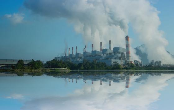 Image of a coal fired power plant by a body of water. Canva image.