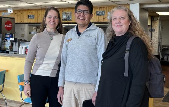 Two women posing with a National Parks staff member in a cafe